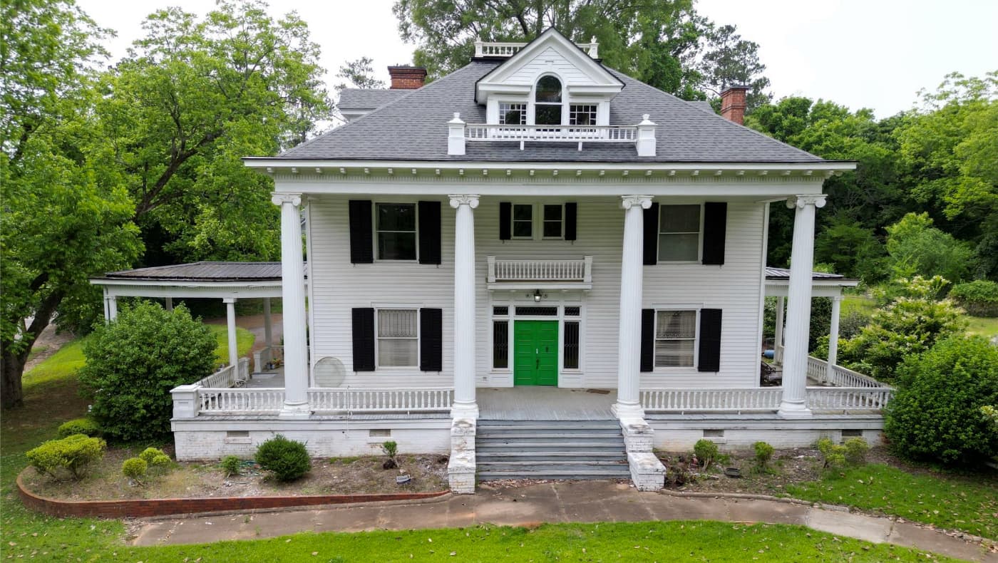 Exterior of the historic Rose Home for sale in Wadesboro, NC; a stunning transitional Queen Anne and Colonial Revival residence featuring a wraparound porch, intricate woodwork, and a prominent turret on a landscaped lot.