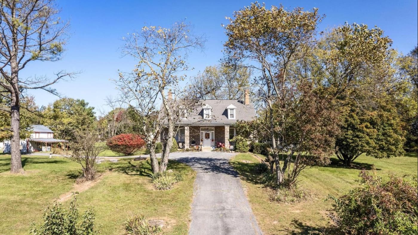 A grand 1912 Colonial Revival stone house with thick limestone walls, wide windowsills, and a circular driveway on a 2.3-acre estate in Shepherdstown, WV.