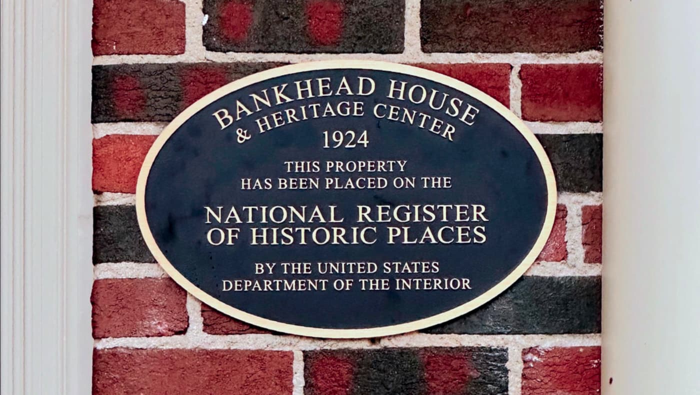 A bronze National Register of Historic Places plaque mounted on the exterior wall of the Bankhead House and Heritage Center.