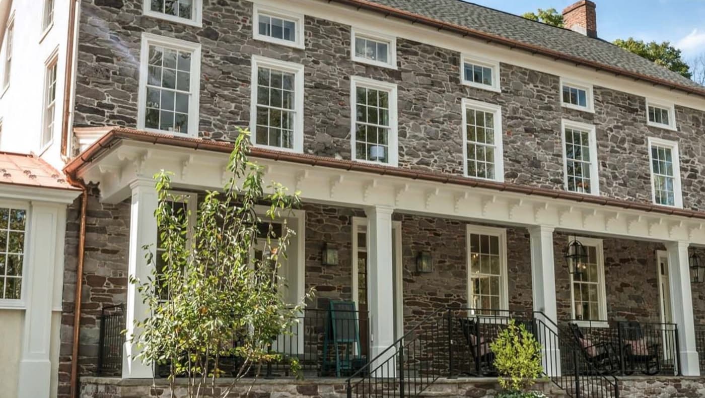 The historic Golden Pheasant Inn in Erwinna, PA, featuring its original 19th-century fieldstone exterior, dark green shutters, and a scenic location along the Delaware Canal.