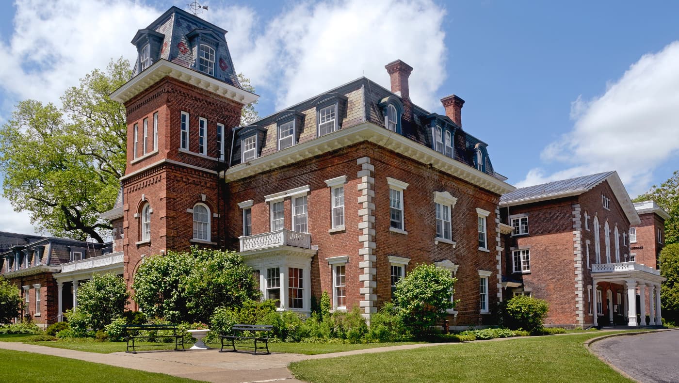 Exterior view of the 93,000-square-foot Oneida Community Mansion House, a National Historic Landmark in New York featuring 19th-century utopian architecture and expansive grounds.