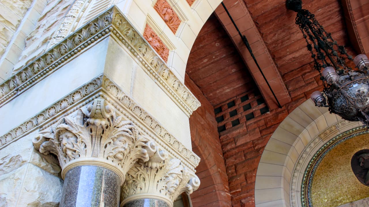 Close-up of the ornate stone arches at the entrance of Olin Library, Cornell University, featuring intricate Gothic Revival stonework and decorative carved faces (grotesques) in Ithaca, NY.