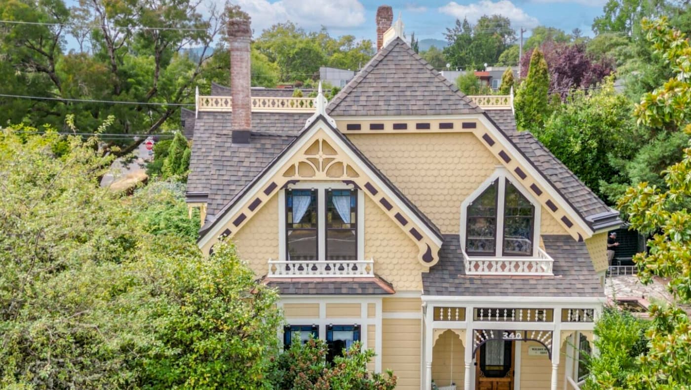 A grand, multi-story Richardsonian Romanesque or Queen Anne style mansion featuring a prominent three-story corner turret with a conical roof.