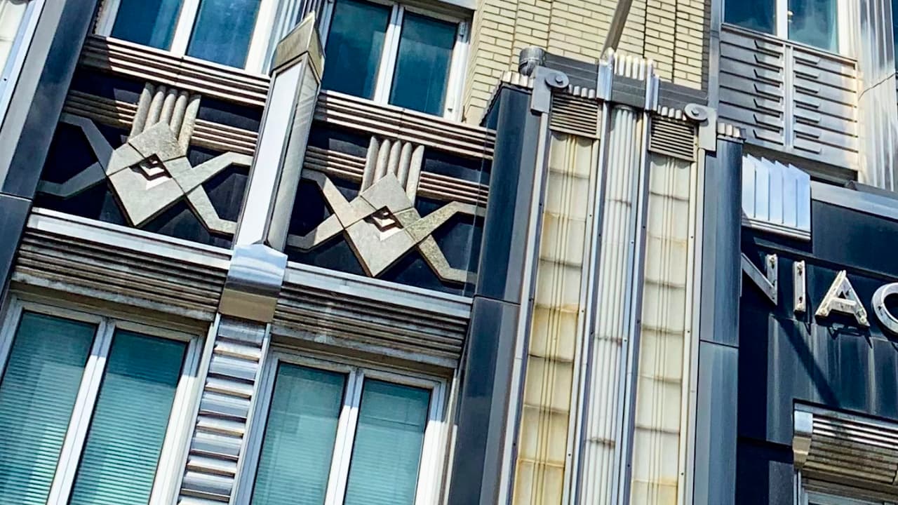 Close-up of the Art Deco exterior of the Niagara Mohawk Building in Syracuse, NY, featuring intricate limestone carvings and prominent Masonic symbols integrated into the facade.
